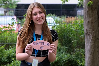 Eine Jugendliche hält eine Karte mit ihrem deutsches Lieblingswort „Schmetterling“ vor sich.
