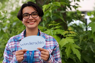Eine Jugendliche hält eine Karte mit ihrem deutsches Lieblingswort „wunderschön“ vor sich.