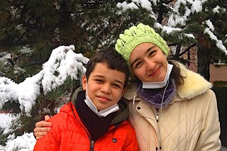Zwei Kinder in winterlicher Kleidung lächeln zufrieden in die Kamera.