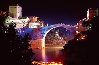 Stari most („Alte Brücke“), das namensgebende Wahrzeichen der Stadt Mostar in Bosnien-Herzegowina, bei Nacht beleuchtet.