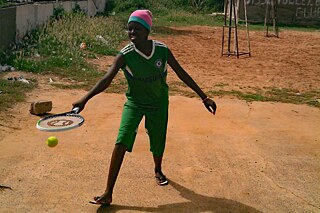 Ein Junge übt mit einem Tennisschläger.
