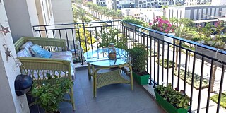 Balkon mit hölzernen Balkonmöbeln und vielen verschiedenen Grünpflanzen in Blumentöpfen