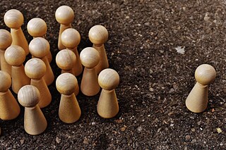 Spielfiguren aus Holz, eine größere Gruppe davon links im Bild, rechts eine einzelne Figur