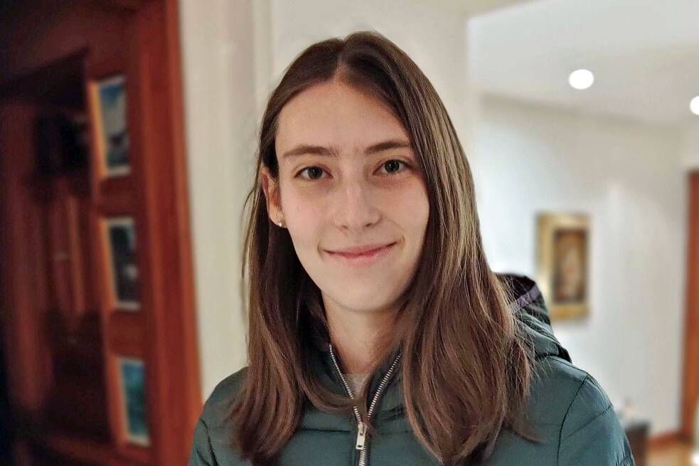 Frau mit braunen Haaren und einem grünen Oberteil in einem Innenraum fotografiert