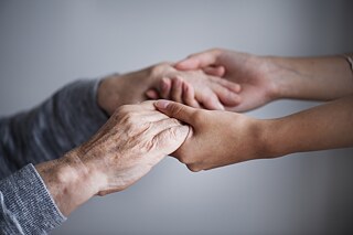 Jüngere und ältere Hände halten aneinander.