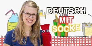 Frau mit einer roten Socke mit aufgeklebten Augen vor einem Bild, auf dem 'Deutsch mit Socke' steht.