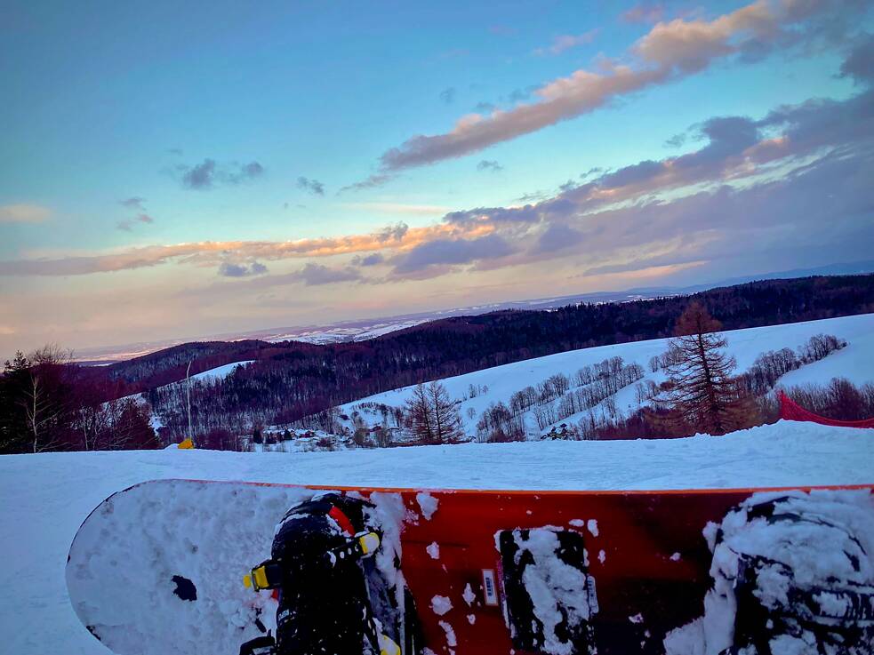 Blick auf eine Schneelandschaft, im Vordergrund ein Snowboard