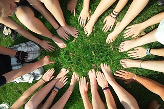 Junge Menschen sitzen im Gras.