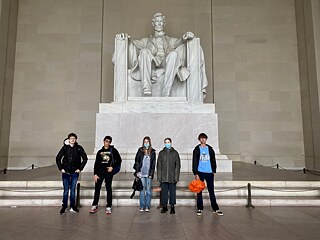 Fünf Jugendliche stehen vor einer Statue eines sitzenden Abraham Lincoln