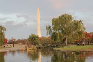 Ein großer Turm, im Vordergrund ein See und Bäume