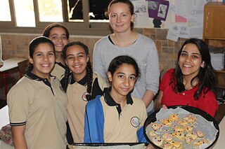 Mehrere Jugendliche stehen für ein Gruppenfoto zusammen und halten ein Blech mit Plätzchen in die Kamera