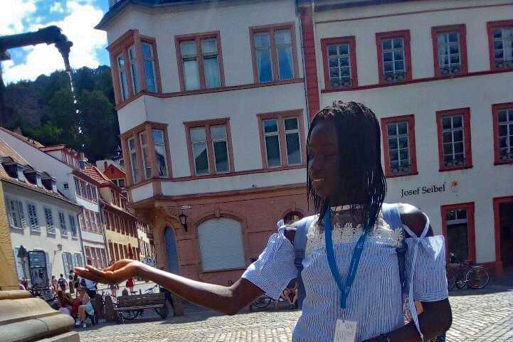 Eine junge Frau steht an einem Brunnen in Pforzheim.