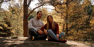 Ein Mann und eine Frau sitzen auf einem Stein in der Natur