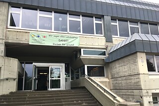 Haupteingang der Schule, zu dem eine Treppe nach oben führt