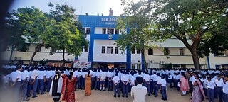 Frontansicht der Don Bosco Matriculation Higher Secondary School mit Menschenmenge