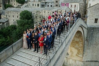 Schülerinnen und Schüler in Abendkleidung auf einer Brücke vor Altstadtkulisse