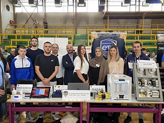 Schülerinnen, Schüler und Lehrkräfte vor einem Stand mit mehreren Projektbeiträgen