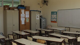 Klassenzimmer mit Tischen, Stühlen, Schränken und Tafel