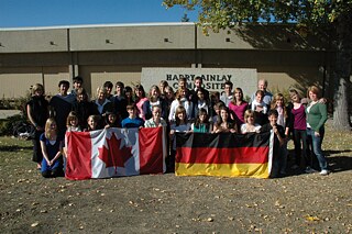 Gruppenfoto vor dem Schulgebäude mit deutscher und kanadischer Flagge