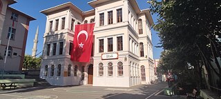 Helles Schulgebäude mit großer türkischer Fahne