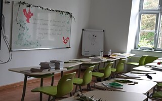 Leeres Klassenzimmer mit Whiteboard und grünen Stühlen