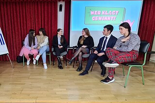 Eine Gruppe Jugendlicher auf einer Bühne. Im Hintergrund eine Projektion mit dem Titel „Wer klagt, gewinnt!“