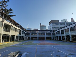 Blick auf Innenhof, umgeben von Schulgebäuden, städtisches Umfeld im Hintergrund