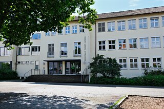 Frontansicht eines weißen, dreistöckigen Schulgebäudes