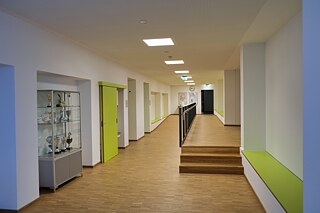 Schulflur mit Holzboden, weiße Wände mit hellblauen und hellgrünen Elementen