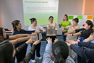 Mongolei: Erlebend lernen Eine Gruppe Jugendlicher und Erwachsener stehen in einer Runde, die Arme strecken sie weit vor sich.