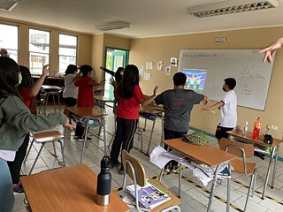 Schülerinnen und Schüler machen Bewegungsübungen im Klassenzimmer