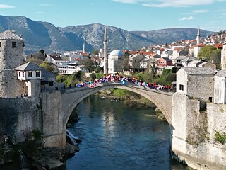 Schülerinnen und Schüler mit Flaggen auf berühmter Brücke von Mostar