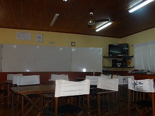 Klassenzimmer mit Stühlen, Tischen, Whiteboard und Fernseher