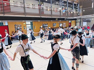Schülerinnnen und Schüler in bayerischer Tracht führen in der Realschule einen Tanz vor