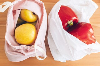 Ein Stoffbeutel mit Äpfel und eine Plastiktüte mit Paprika