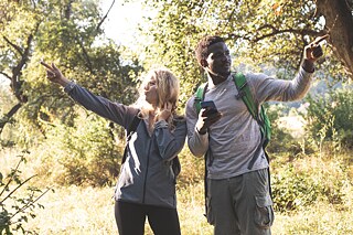 Junge Leute in der Natur zeigen in entgegengesetzte Richtungen.