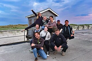 Neun junge, fröhliche Menschen am Nordseestrand.