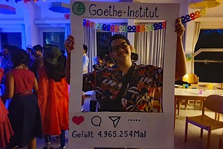 Ein Jugendlicher hällt einen Rahmen aus weißem Karton in die Höhe, darauf steht: Goethe-Institut gefällt 4.965.245 Mal.