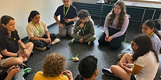 Jugendliche sitzen auf dem Fußboden und spielen UNO