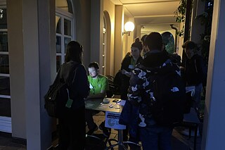 Abendaufnahme: In einer leicht beleuchteten Gallerie steht ein Tisch und es wird offenbar noch gearbeitet.