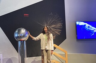 Bandgenerator Jugendliche an einem Bandgenerator, ihr stehen die langen Haare „zu Berge“.