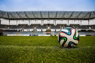 Ein Fußball auf einem Fußballfeld, im Hintergrund ein leeres Tor