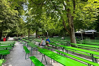 Ein Biergarten Ein Biergarten mit Bänken und Tischen unter Bäumen