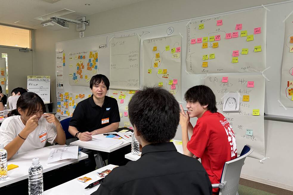 Jugendlicher beim Workshop „KI im Mittelpunkt“. Hinter ihnen hängt eine weiße Tafel mit bunten Post-It an der Wand.