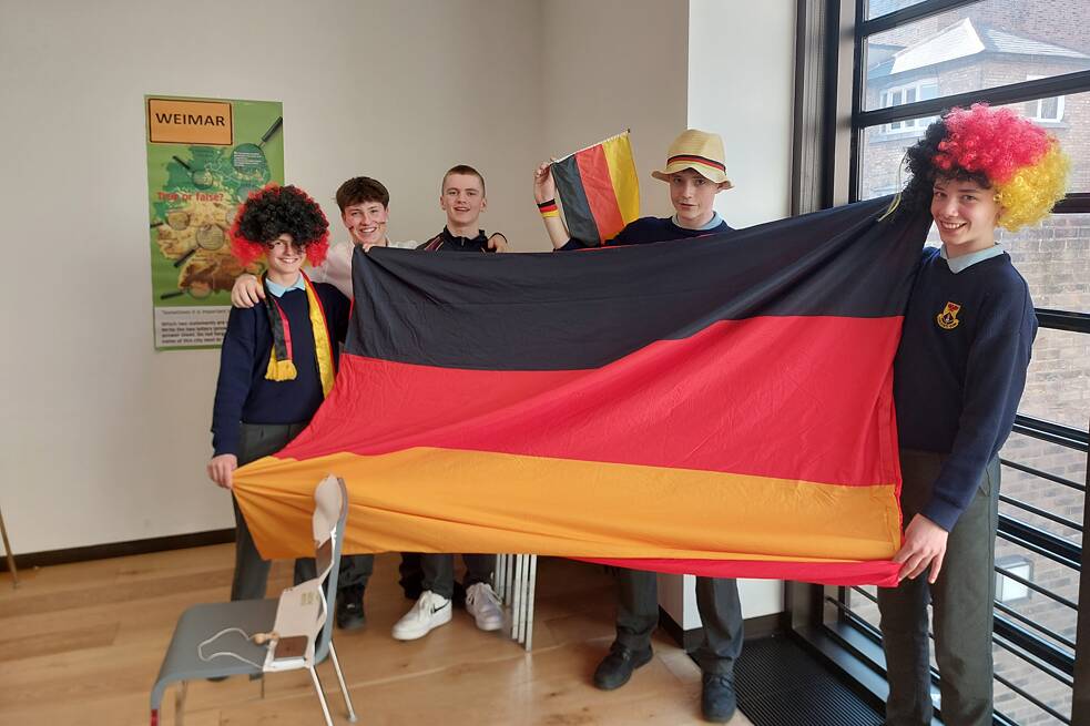 Jugendliche in Schuluniform halten eine Fahne der Bundesrepublik Deutschland.