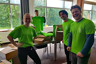 Junge Leute in knallgrünen T-Shirts mit Logo lächeln in die Kamera.