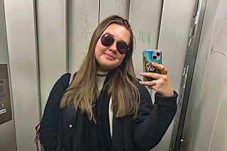 Eine junge Frau mit Sonnenbrille und Smartphone in einem Aufzug