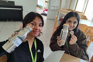 Zwei junge Frauen halten ihre selbst gestalteten Trinkflaschen in die Kamera.