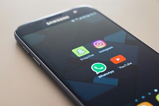 Ein Smartphon auf dessen Bildschirm vier weit verbreitete Apps angezeigt werden.