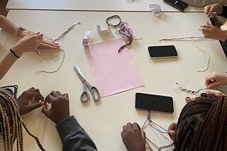 Jugendliche knüpfen Freundschaftsarmbänder.